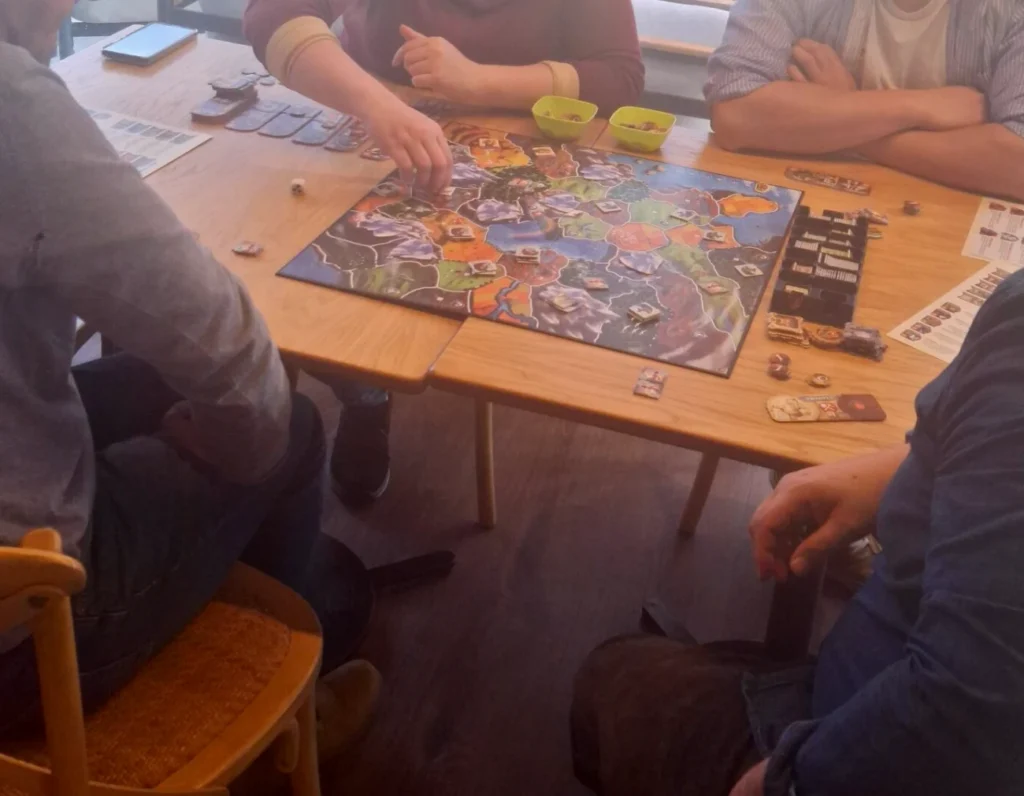 Equipa à volta de uma mesa com um jogo de tabuleiro de mapa, cartas e peças