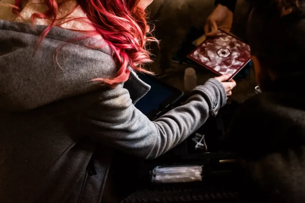 Jogadora a abrir o kit do escape game, com o iPad e um caderno de pistas