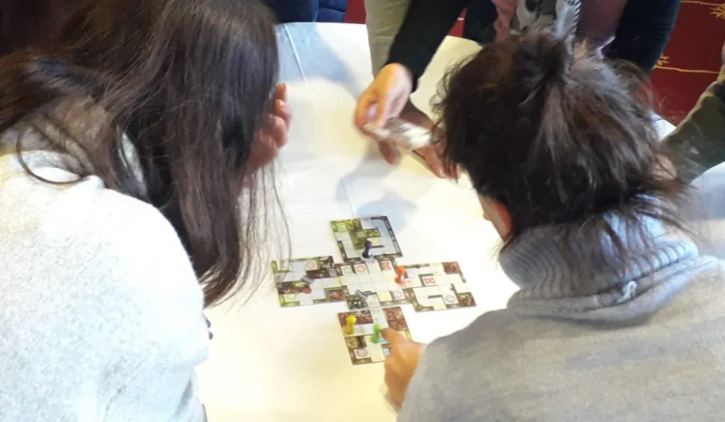 Equipa à volta de uma mesa a jogar um jogo de tabuleiro cooperativo numa sessão de team building