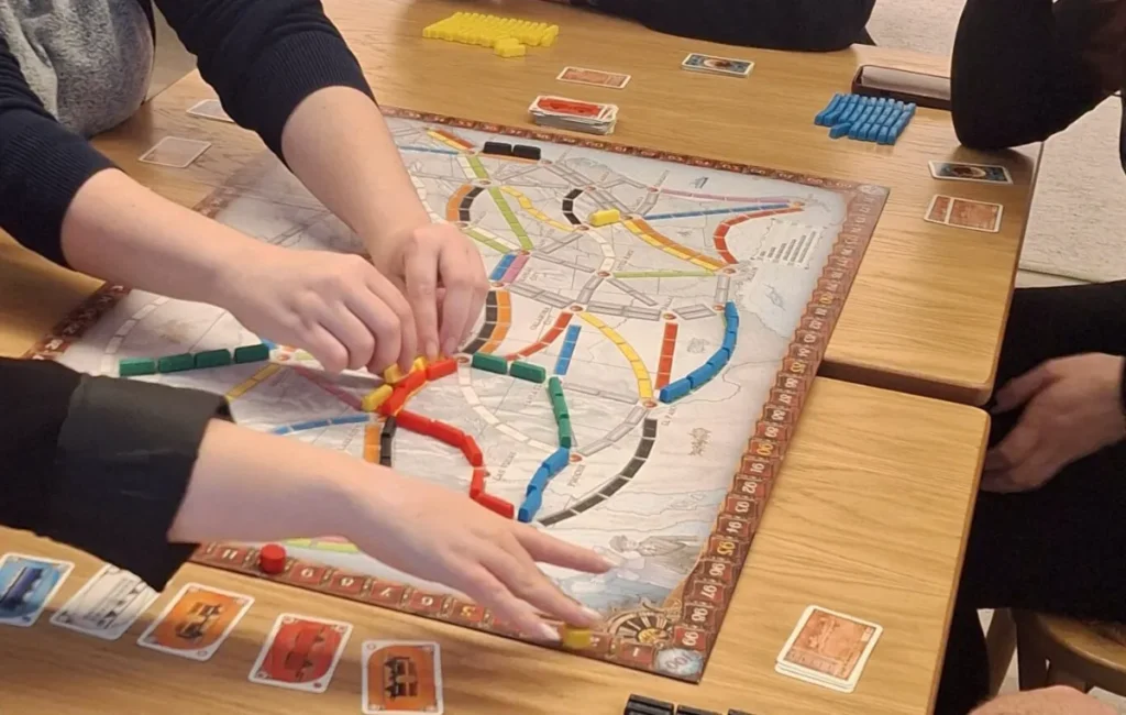 Mãos de uma equipa a colocar comboios num jogo de tabuleiro, numa sessão de team building